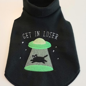 May include: Black turtleneck sweater for a pet with a green alien spaceship and a black cat inside. The text "GET IN LOSER" is embroidered on the sweater.