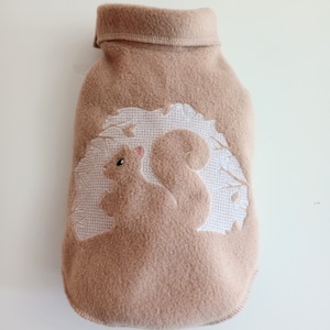May include: A brown fleece dog sweater with a white embroidered squirrel design.