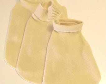May include: Three cream-colored turtleneck sweaters in different sizes, stacked on top of each other.