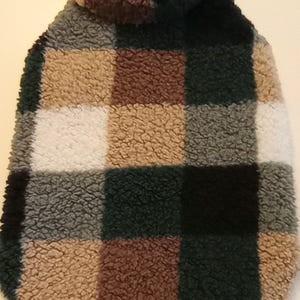 May include: A plaid dog sweater with a high neck collar. The sweater is made of a soft, fuzzy material and features a brown, green, black, and white plaid pattern.