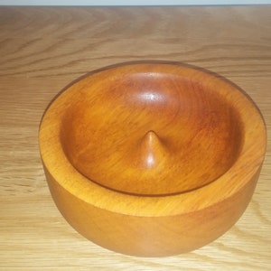 Puede incluir: Un cuenco de madera con un centro puntiagudo, hecho de madera marrón claro.