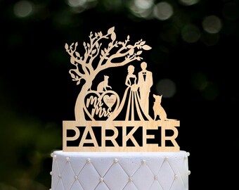 Puede incluir: Topper de pastel de boda de madera con una pareja, dos perros y un árbol con las palabras "Mr. & Mrs. Parker" y la fecha "14.08.2004".