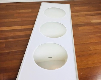 May include: A white rectangular mirror with a silver frame. The mirror has three circular openings, each with a reflective surface.