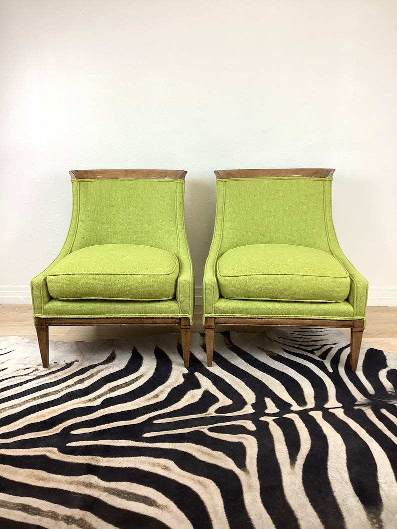 May include: Two lime green armchairs with wooden frames and legs. The chairs have a rectangular back with a curved top and a cushioned seat. The chairs are placed on a zebra-striped rug.