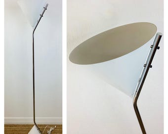 May include: A white floor lamp with a chrome metal base and a white cone-shaped shade. The lamp is adjustable and can be tilted up or down.