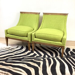 May include: Two lime green upholstered armchairs with wooden frames and legs. The chairs have a curved back and a square seat cushion. The chairs are placed on a zebra-striped rug.