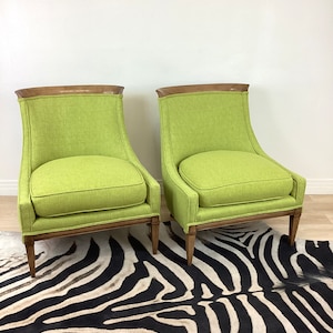 May include: Two lime green upholstered armchairs with wooden frames and legs. The chairs have a curved back and a cushioned seat. The chairs are placed on a zebra print rug.