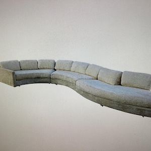 May include: A large, curved, light gray sectional sofa with multiple cushions.