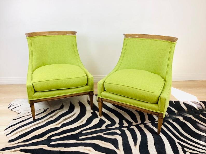 May include: Two lime green armchairs with wooden frames and a zebra-print rug. The chairs have a curved back design and a light wood trim at the top. The rug is black and white.