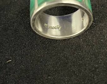 May include: A silver ring with a green malachite inlay. The ring is engraved with the word "Timothy".