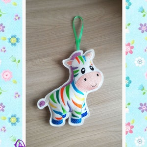May include: A colourful rainbow zebra plush toy with a green hanging loop. The zebra has a white background with rainbow stripes and a pink nose.