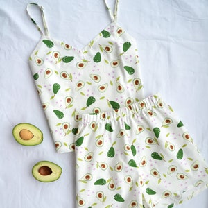 Può includere: Pigiama bianco con stampa di avocado verde. La parte superiore è un top senza maniche e la parte inferiore è un pantaloncino.
