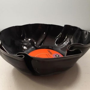 May include: A black vinyl record bowl with a red and white label that says "Capitol Records" and a purple center label. The bowl is made from a recycled vinyl record.