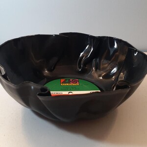May include: A black vinyl record has been repurposed into a bowl. The record label is visible in the bottom of the bowl and reads "ATLANTIC" and "FIRST TAKE" in white text on a green background.