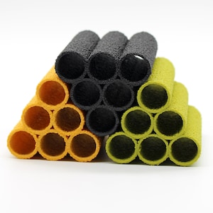 May include: A set of black, yellow and green foam pipe-shaped tubes stacked in a triangular pattern. The tubes have a textured surface and are designed to be used as a toy or for crafts.