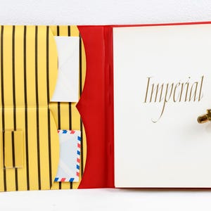 Cartella portadocumenti anni '50 con spazio per buste, blocco note e una cartellina separata per francobolli. Plastica gialla con decoro a righe e chiusura.