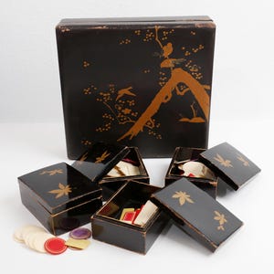 Caja de juego con 4 cajas con tapa llenas de fichas de hueso. También una serie de cartas antiguas.