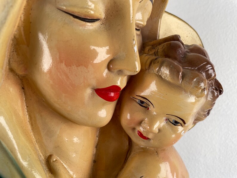 Peut inclure: Une sculpture en pl&acirc;tre vintage de la Vierge Marie tenant un b&eacute;b&eacute; J&eacute;sus. La sculpture est peinte en cr&egrave;me avec des l&egrave;vres rouges et des cheveux bruns. La sculpture est en gros plan.