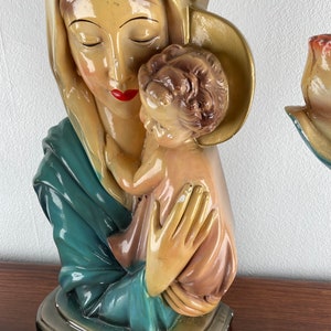 Peut inclure: Une statue en pl&acirc;tre vintage de la Vierge Marie tenant un b&eacute;b&eacute; J&eacute;sus. La statue est peinte dans des tons de bleu, vert, jaune et rose.