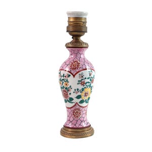 Può includere: Una lampada da tavolo decorativa con base in ceramica rosa con un motivo floreale rosso, giallo e verde. La lampada ha una parte superiore e una base in metallo color ottone e un portalampada bianco.