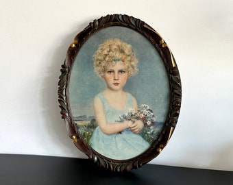 Impression d'art encadrée dans un beau cadre en bois richement décoré avec des détails dorés, portrait d'une jeune fille aux boucles blondes, bouquet de fleurs