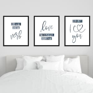 Op de afbeelding: Drie zwarte ingelijste prints met witte achtergronden en blauwe aquarel accenten. De prints bevatten de tekst "love is a verb", "love without limits" en "p.s. I love you".