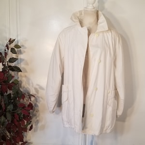 May include: A white jacket with a button closure and two pockets. The jacket has a drawstring at the waist.