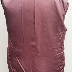 May include: Back view of a dark navy blazer with a black collar. The inside lining is a deep burgundy color, with a smooth, satin-like texture. The blazer is displayed on a white mannequin.