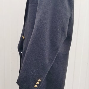 May include: A dark navy blazer with gold-colored buttons. The blazer has a classic design with a notched lapel and a tailored fit. The sleeves have three buttons. The blazer is displayed on a white mannequin.
