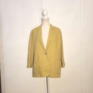 May include: A yellow blazer with a black polka dot pattern. The blazer has a single button closure and long sleeves.