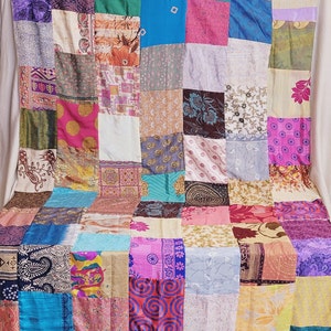 May include: A patchwork quilt made from a variety of colorful fabrics. The quilt is made up of squares of different sizes and colors, and the fabrics are all different patterns. The quilt is a beautiful example of handmade craftsmanship.