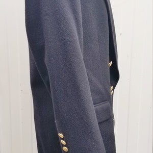 May include: A dark navy blazer with gold-colored buttons. The blazer has a classic design with a notched lapel and a tailored fit. The buttons are round and shiny, adding a touch of elegance to the garment.