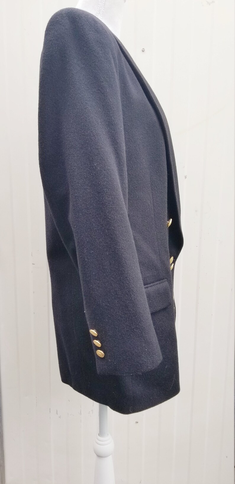 May include: A dark navy blazer with gold-colored buttons. The blazer has a classic design with a notched lapel and a tailored fit. The buttons are round and shiny, adding a touch of elegance to the garment.