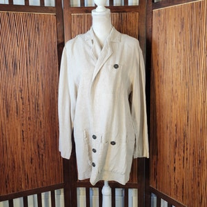 May include: A long-sleeved, beige linen jacket with a double-breasted closure and multiple pockets. The jacket has a relaxed fit and a slightly oversized silhouette.