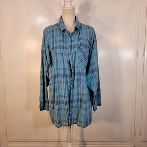 May include: A blue and green plaid long-sleeved button-up shirt with a single chest pocket.