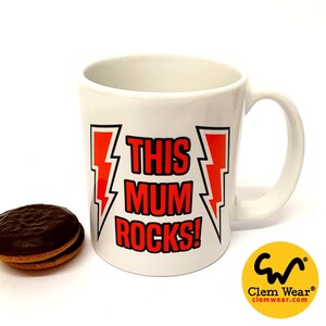 Op de afbeelding: Witte keramische mok met een rode bliksemgrafiek en de tekst "This Mum Rocks!" in zwarte letters.