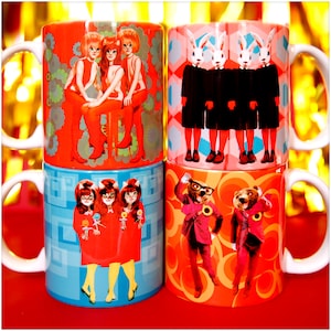 May include: Four ceramic mugs with different colourful designs. The first mug features three women in red dresses with a floral background. The second mug features four white rabbits in black suits with a geometric background. The third mug features three women in red dresses with a blue and white geometric background. The fourth mug features two bears in suits with a red and white geometric background.