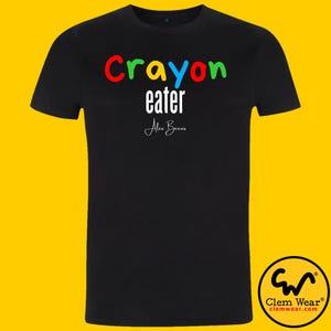 May include: Black t-shirt with the text "Crayon eater" in colourful letters and the text "Alex Becon" in white.