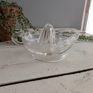 Puede incluir: Exprimidor de cítricos de vidrio transparente con un reamer acanalado y un pico vertedor. El exprimidor tiene una base redonda y un asa. Ideal para exprimir zumo fresco de cítricos.