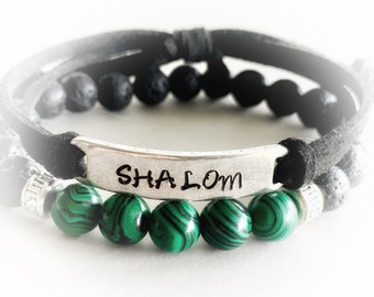 May include: A black leather bracelet with a silver charm that says "SHALOM" and green malachite beads.