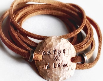 May include: A brown leather wrap bracelet with a silver charm that says "carpe diem" with a sun symbol.