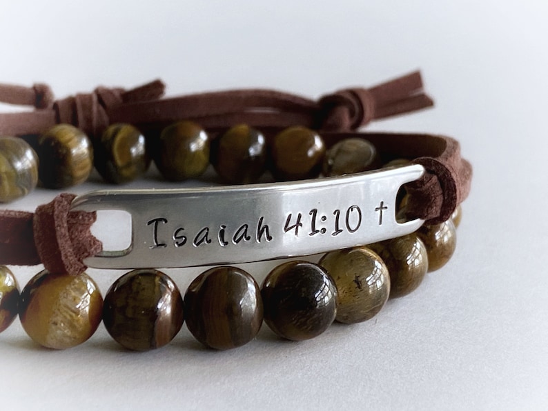 May include: Brown leather bracelet with tiger's eye beads and a silver charm engraved with "Isaiah 41:10 +"