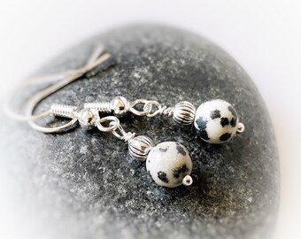 May include: Dalmatian jasper earrings with sterling silver ear wires. The earrings feature round, speckled beads in shades of white, gray, and black. The silver components include small beads and decorative accents.