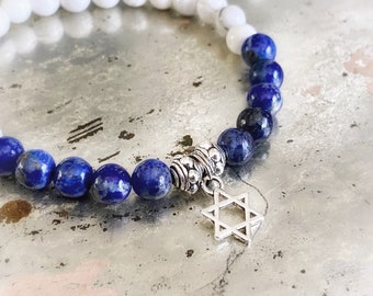 May include: A blue and white beaded bracelet with a silver Star of David charm. The bracelet is made with lapis lazuli and white jade beads.