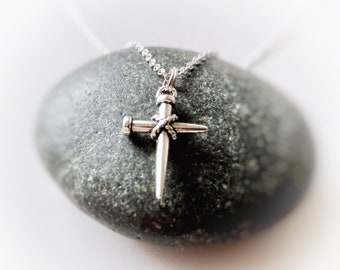 May include: Silver necklace with a cross pendant made of a nail with a twisted wire design.