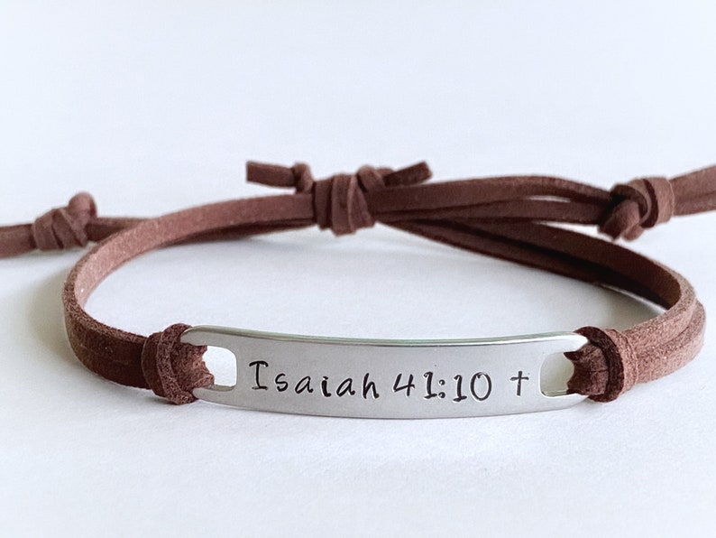 May include: Brown leather cord bracelet with a silver metal tag that reads "Isaiah 41:10 +"