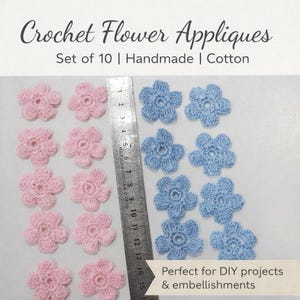 Könnte beinhalten: Häkelblumen-Applikationen in Rosa und Blau. Das Set enthält zehn handgefertigte Baumwollblumen, perfekt für DIY-Projekte und Verzierungen. Ein Lineal liegt neben den Blumen.