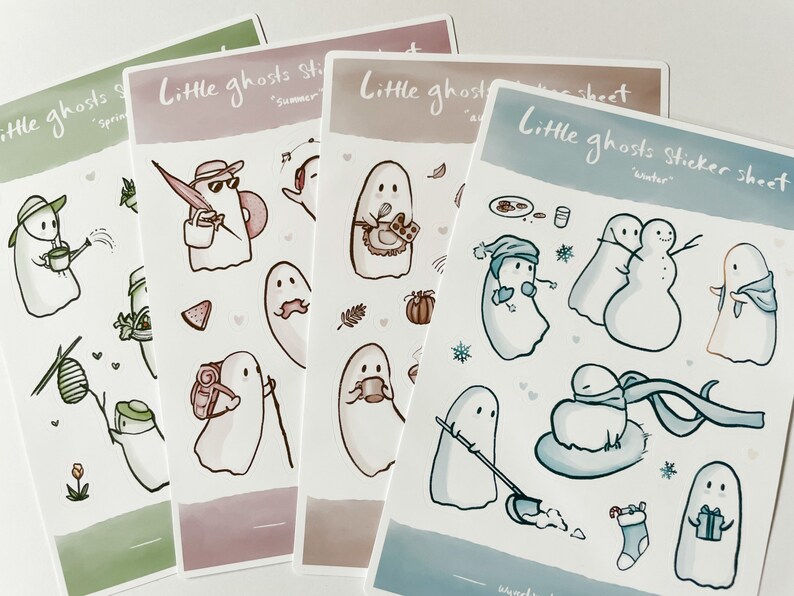 May include: Four sticker sheets featuring illustrations of ghosts in different seasons. The sheets are labeled "Little ghosts sticker sheet" with the season name below. The spring sheet features a green background with a ghost watering a plant. The summer sheet features a pink background with a ghost wearing a hat and sunglasses. The autumn sheet features a brown background with a ghost holding a cup of coffee. The winter sheet features a blue background with a ghost wearing a hat and scarf.