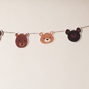 May include: A brown and tan bear head garland with five bear heads strung on a twine string.