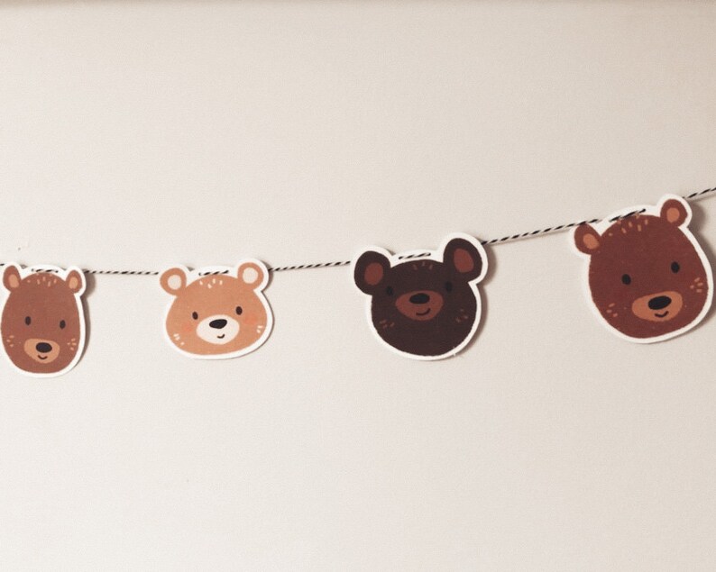 May include: A brown and black bear face garland with four bear faces strung on a white string.